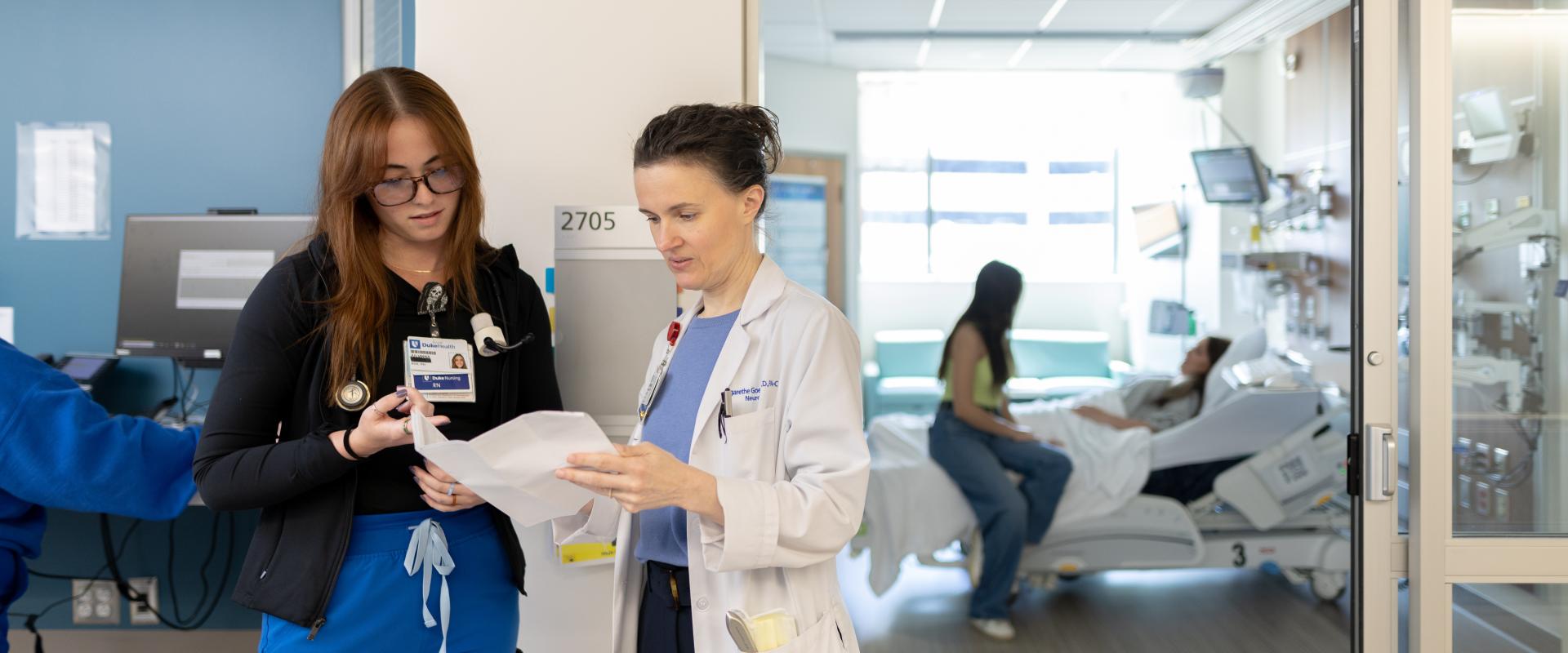 Nurse and doctor reading a patient chart outside hospital room 